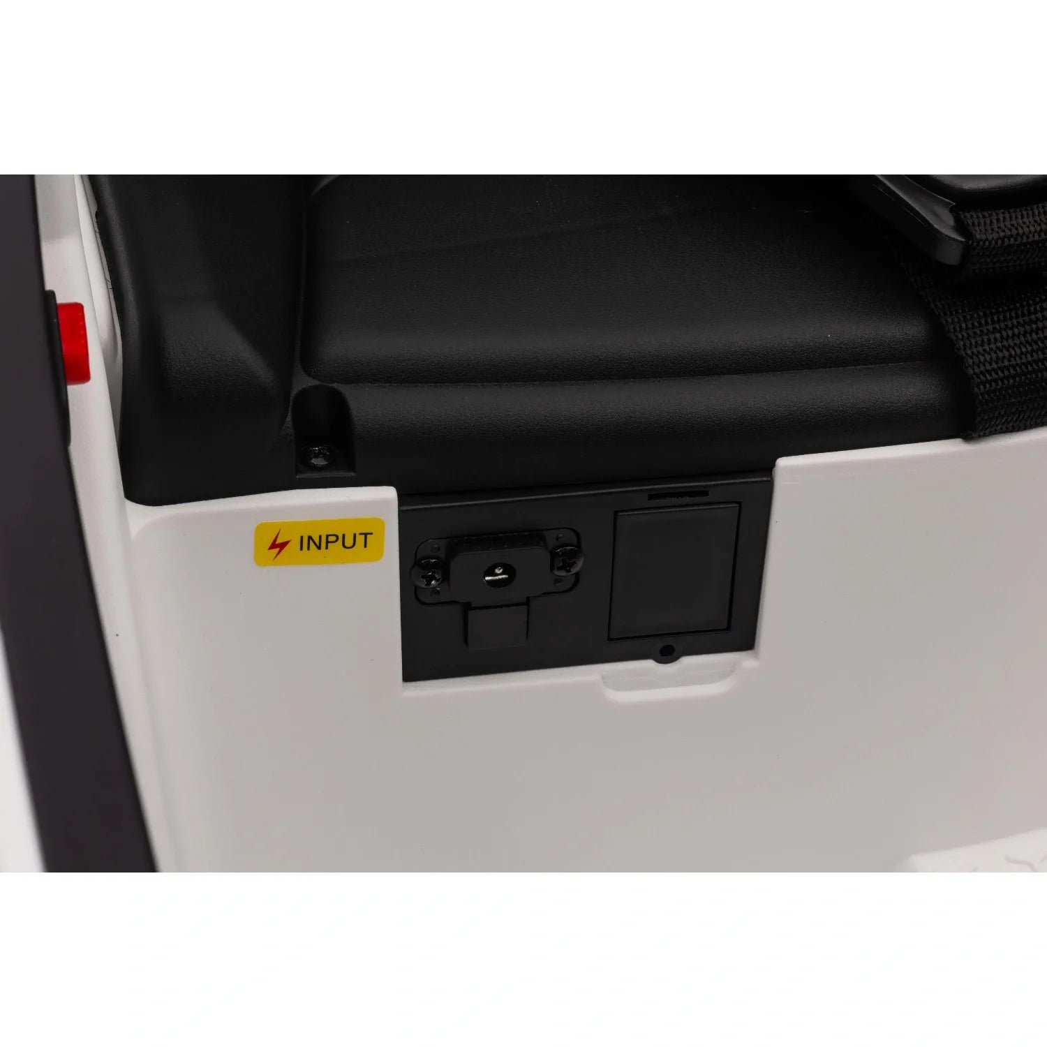 Close-up of white kids electric ride-on car charging input panel near black seat cushion