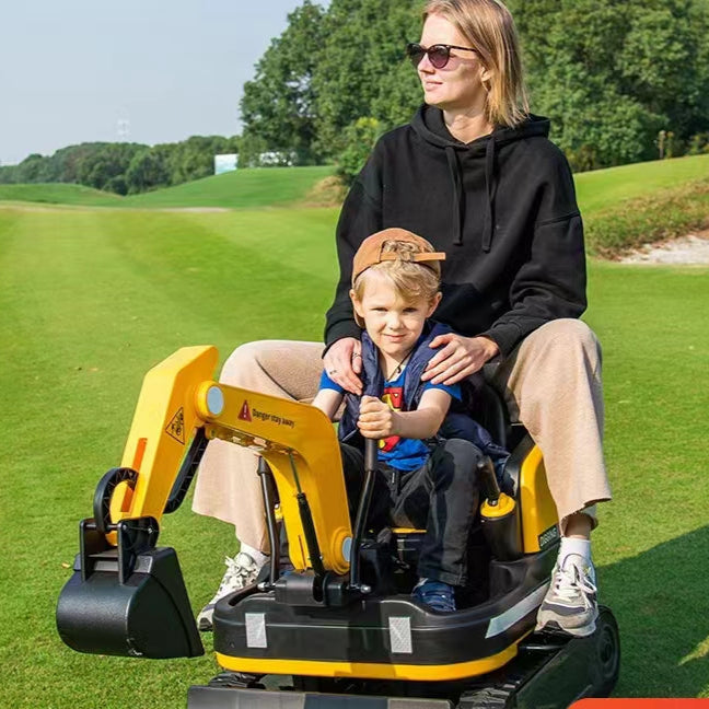 Woman and child playing on a toy excavator in a grassy field