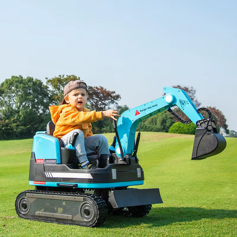 Toddler wearing a cap and orange hoodie sitting on a blue 24V ride-on excavator digger on grass outdoors