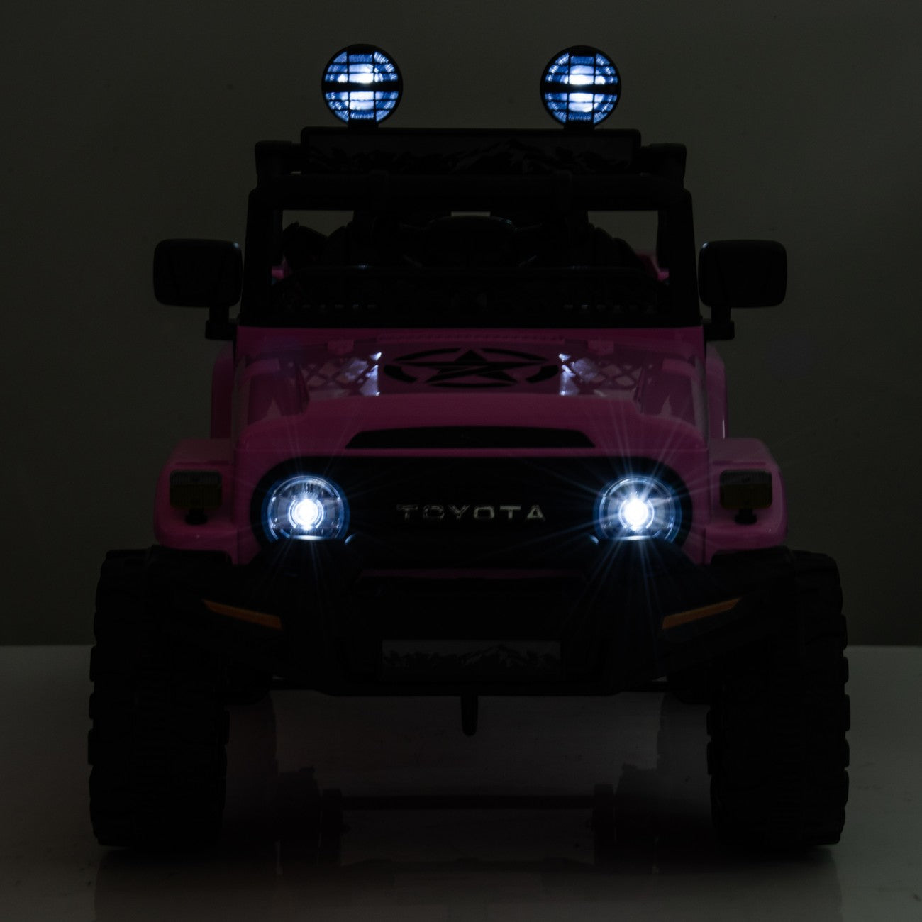 Front view of pink Toyota FJ Cruiser licensed electric ride-on toy car with headlights and spotlights on