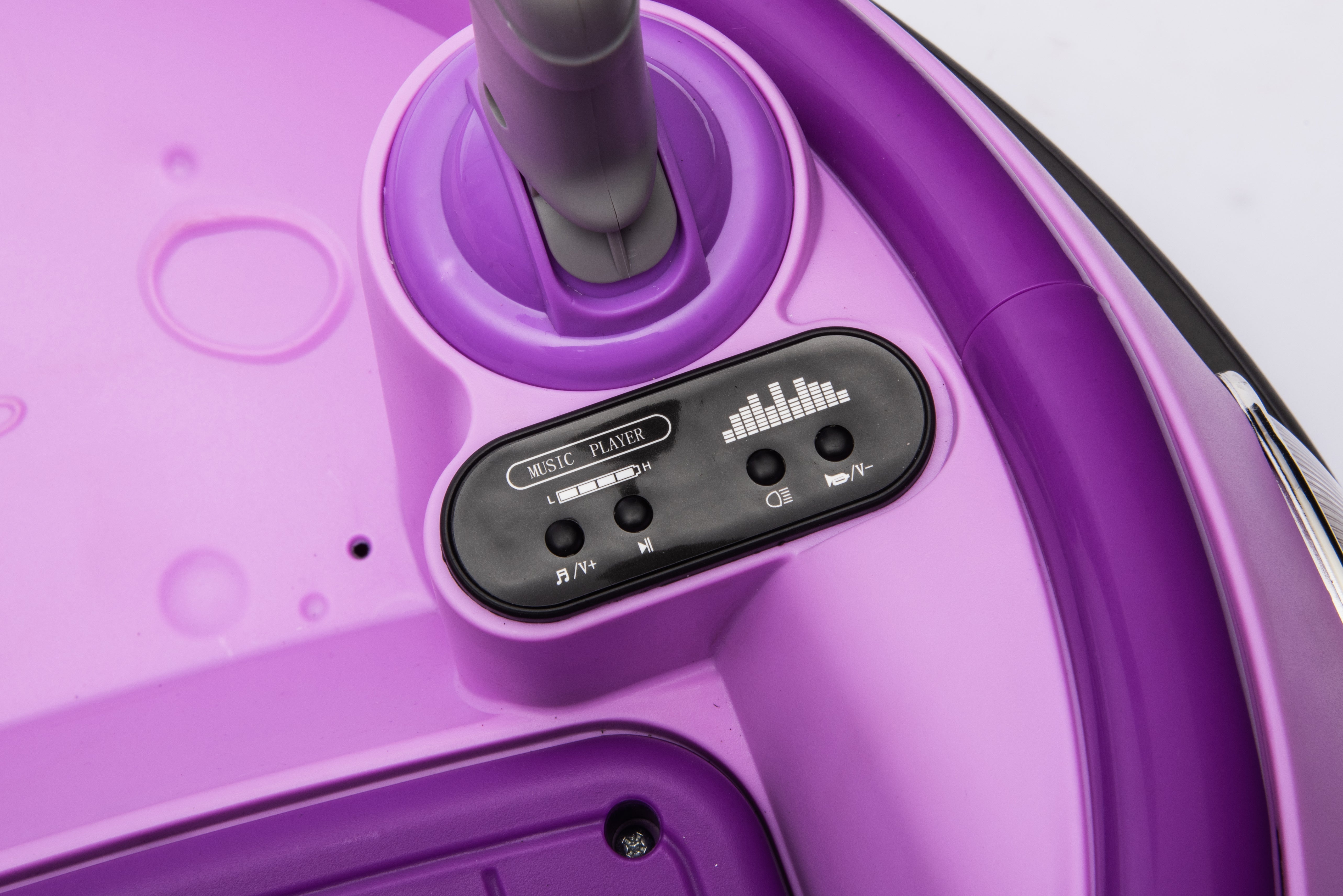 Close-up of purple kids bumper car music player controls with play, pause, and volume buttons on the dashboard panel.