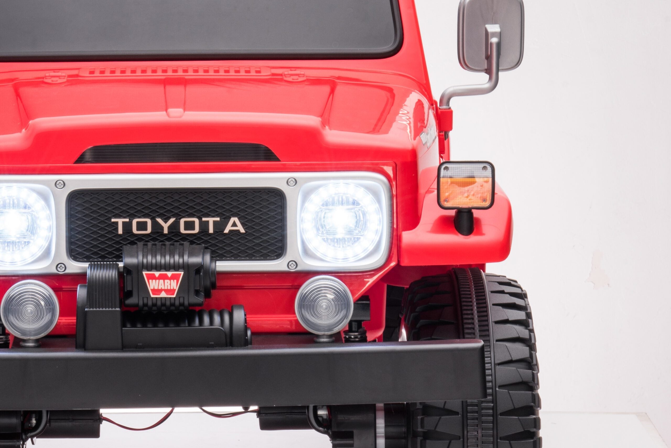 Front view of the red Licensed Toyota FJ40 LandCruiser kids ride-on SUV with headlights on and detailed grille.