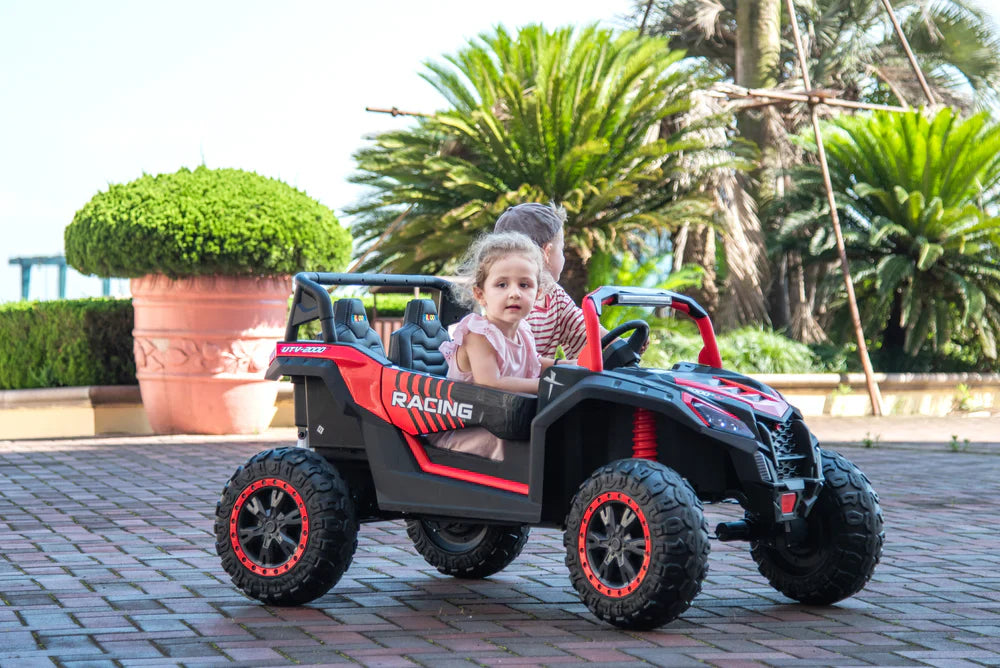 Two children riding a black and red Stinger Buggy XL 24V 4x4 two-seater kids ride-on car outdoors