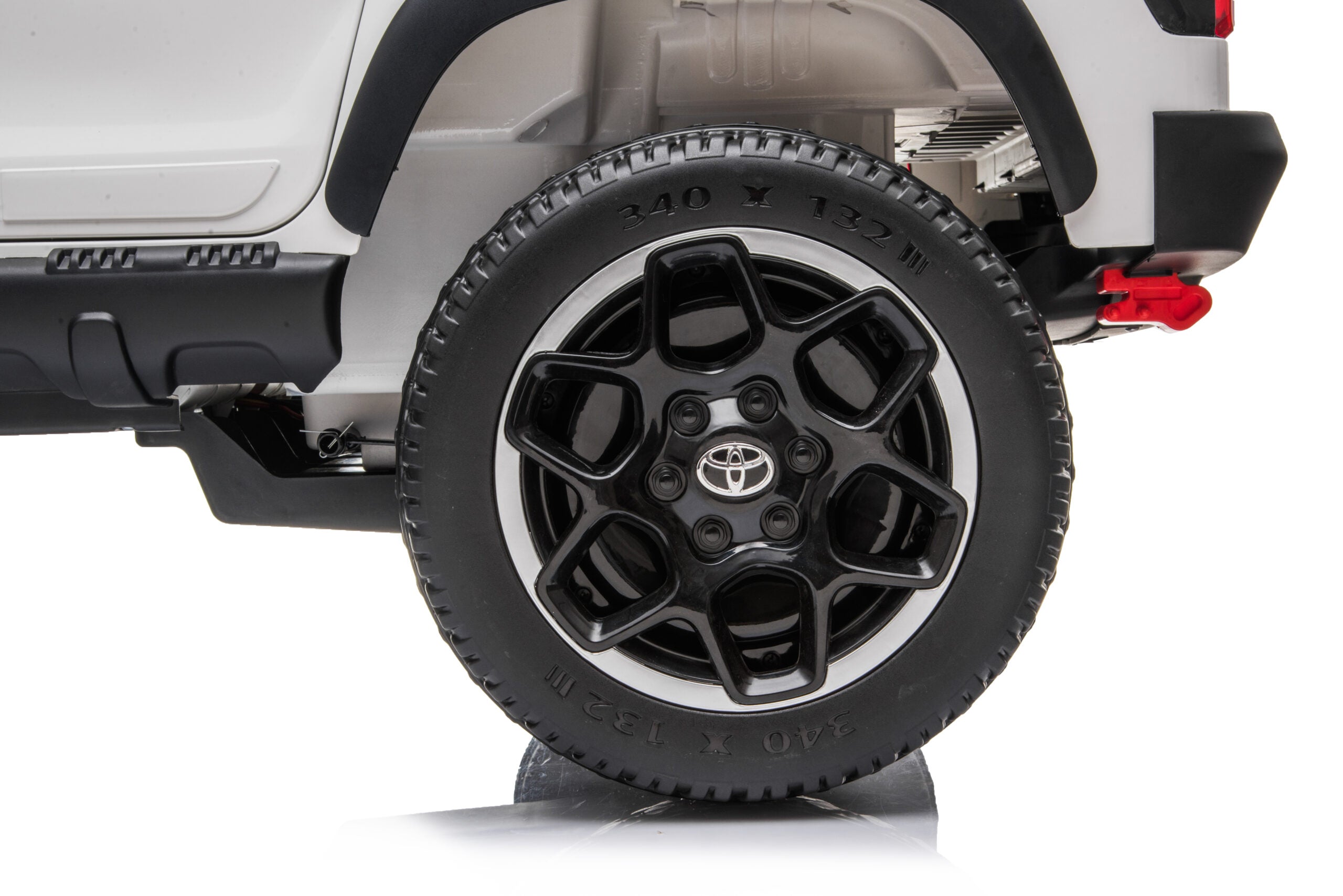 Close-up of the black alloy wheel with Toyota logo on the licensed white Toyota Hilux kids ride-on car.