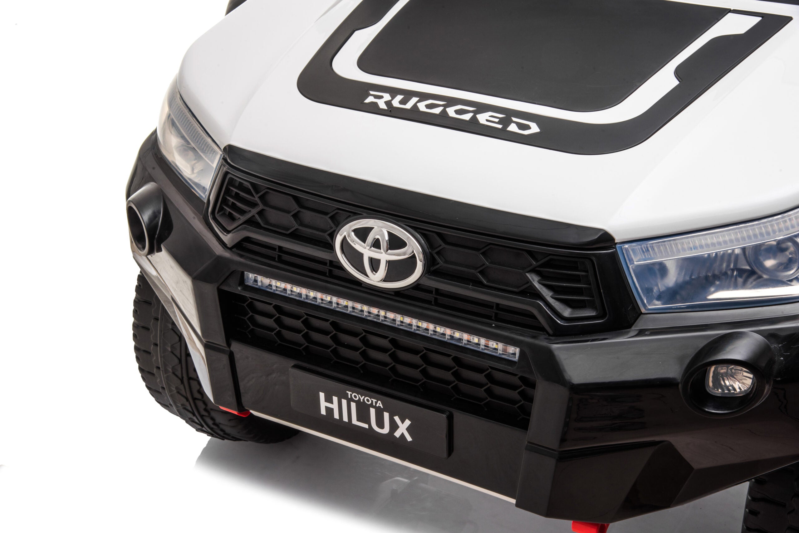 Close-up of the white Licensed Toyota Hilux Rugged 24V kids ride-on car front grille and headlights.