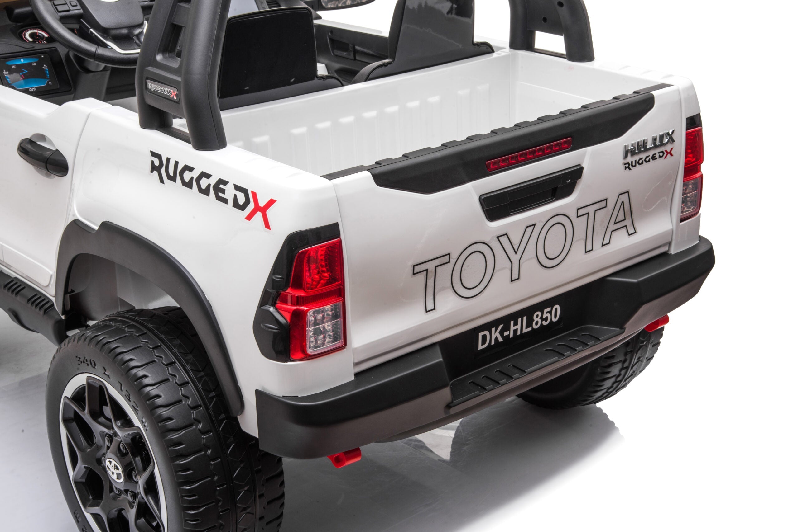 Rear view of white Licensed Toyota Hilux Rugged 24V Kids Ride-On Car with detailed tailgate and rugged tires