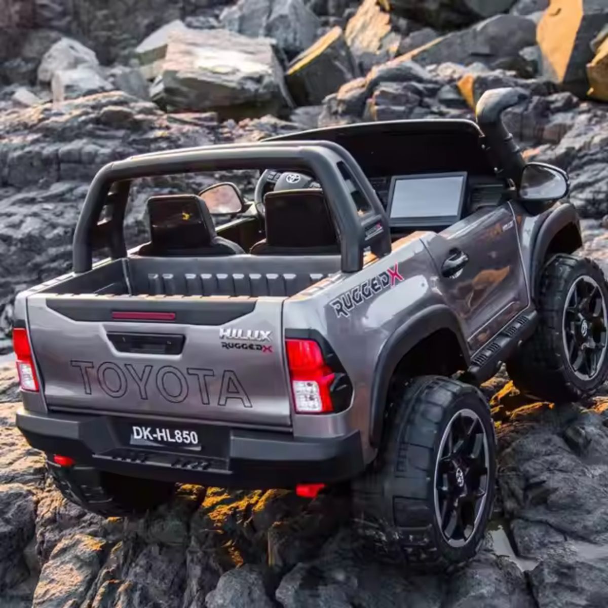 Grey Licensed Toyota Hilux Rugged 24V Kids Ride-On Car with 4×4 drive, 2 leather seats, and realistic details on rocky terrain