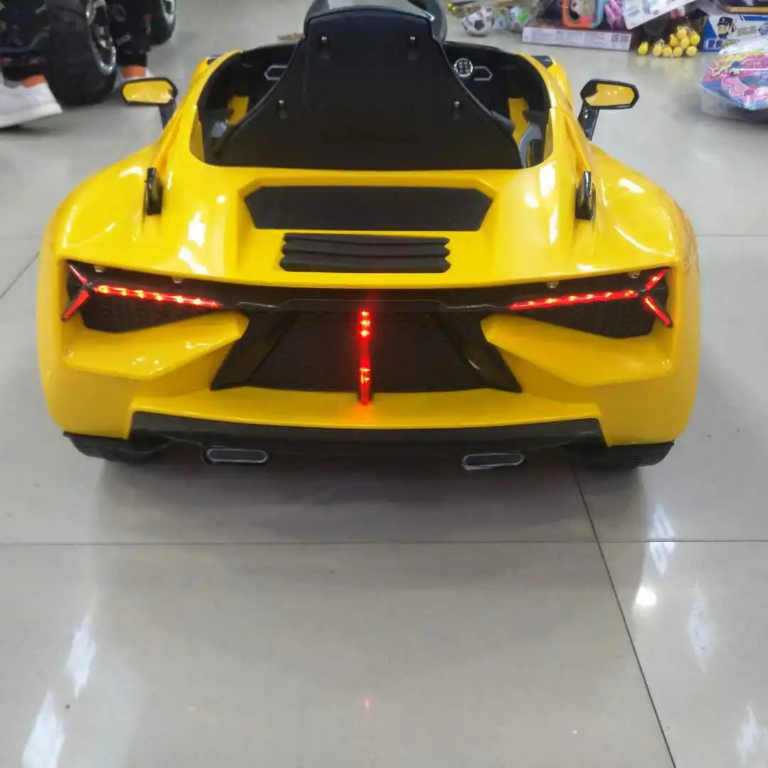 Yellow kids ride-on sports car with single seat and rear LED lights on a showroom floor