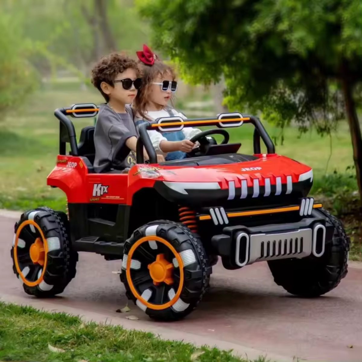 Two children wearing sunglasses riding a red 24V 2-seater electric UTV buggy outdoors on a paved path.