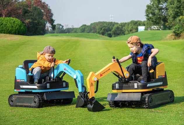 Two children playing outdoors on blue and yellow ride-on excavator diggers with working arms on grass field