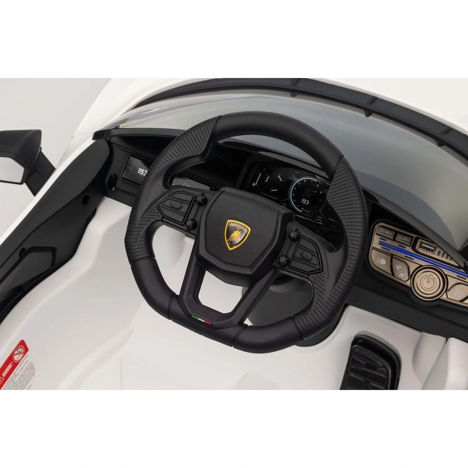 Close-up of black steering wheel with Lamborghini emblem inside white 12V kids electric ride-on car dashboard