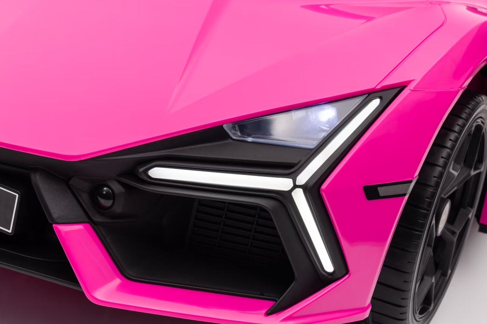 Close-up of the front LED headlight and grille detail on a pink Lamborghini Revuelto 12V kids ride-on car.