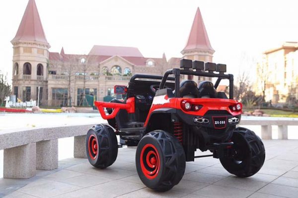 Red 12V 4WD kids ride-on monster truck buggy with rugged off-road tires and remote control parked outdoors.