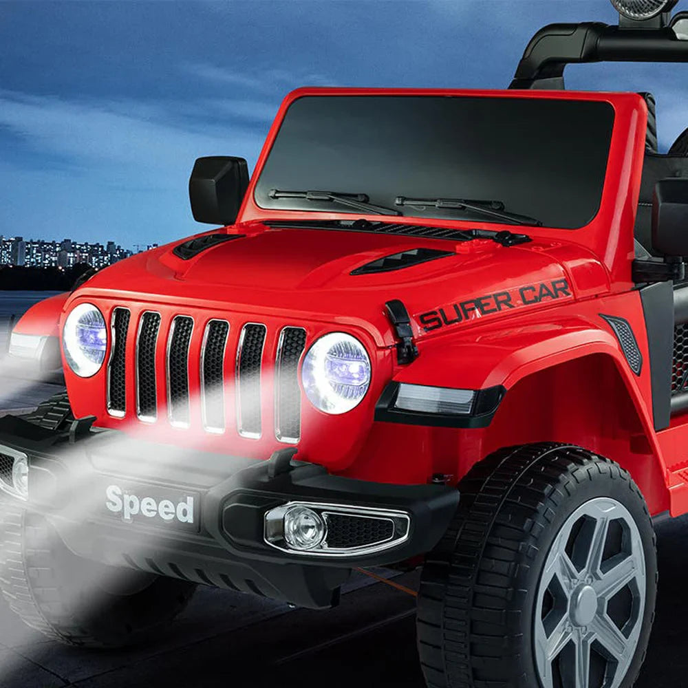 Red 12V kids Jeep Wrangler ride-on car with headlights on, rugged tires, and black tinted windshield at night