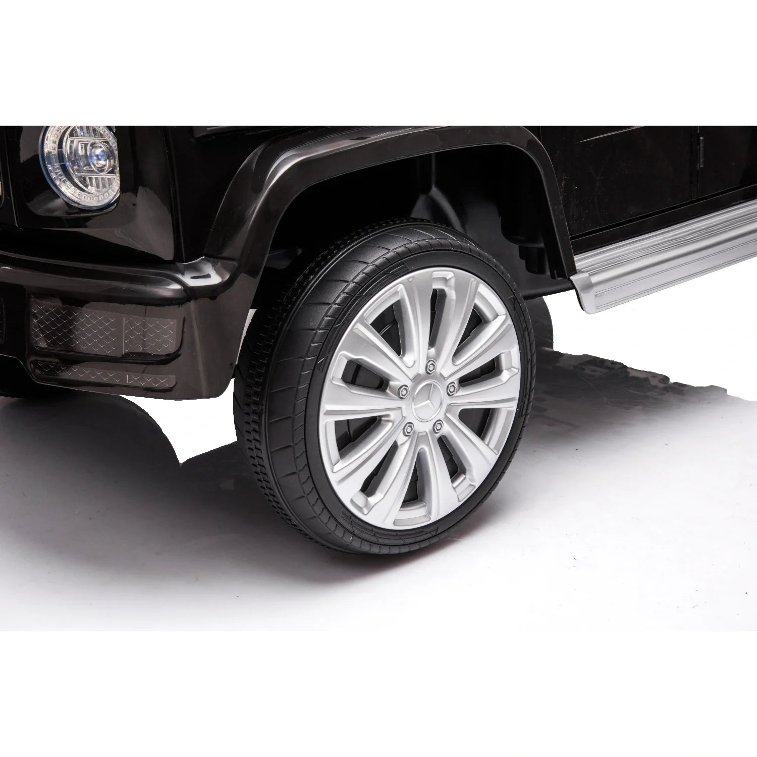 Close-up of silver alloy wheel and black tire on black Mercedes G-Wagon G63 kids electric ride-on car